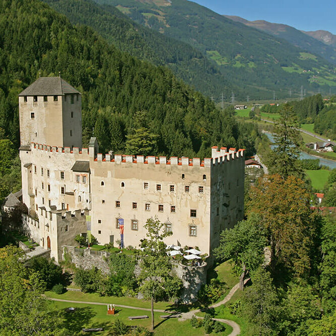 Sommerliche Ansicht des Schlosses Bruck mit dem Iselfluss im Hintergrund