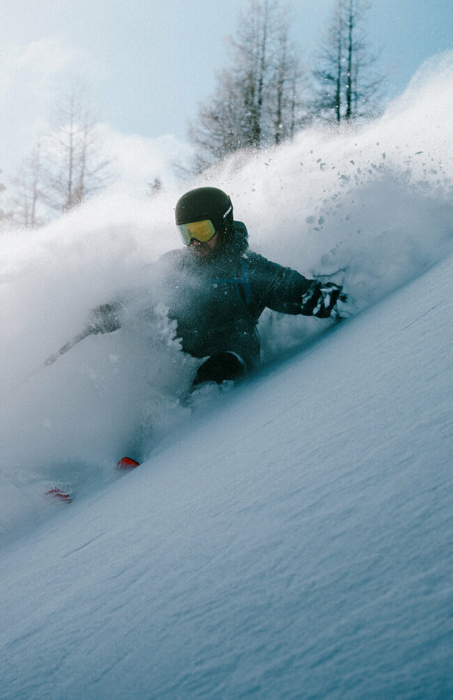 Ein Skitourenfahrer bei der Abfahrt von der Roten Wand im Defereggental. Er fährt durch Tiefschnee und Trägt Helm, Skibrille und Stöcke. 