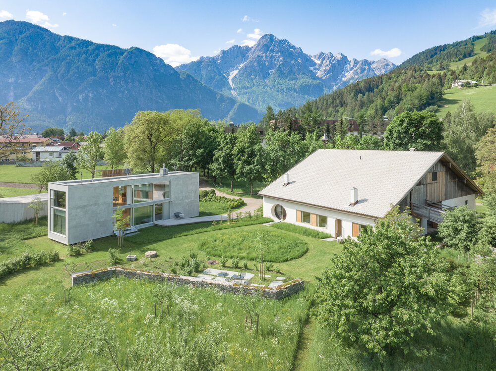 Außenansicht des Iselhof in Lienz mit großem Garten und im Hintergrund die Lienzer Dolomiten.