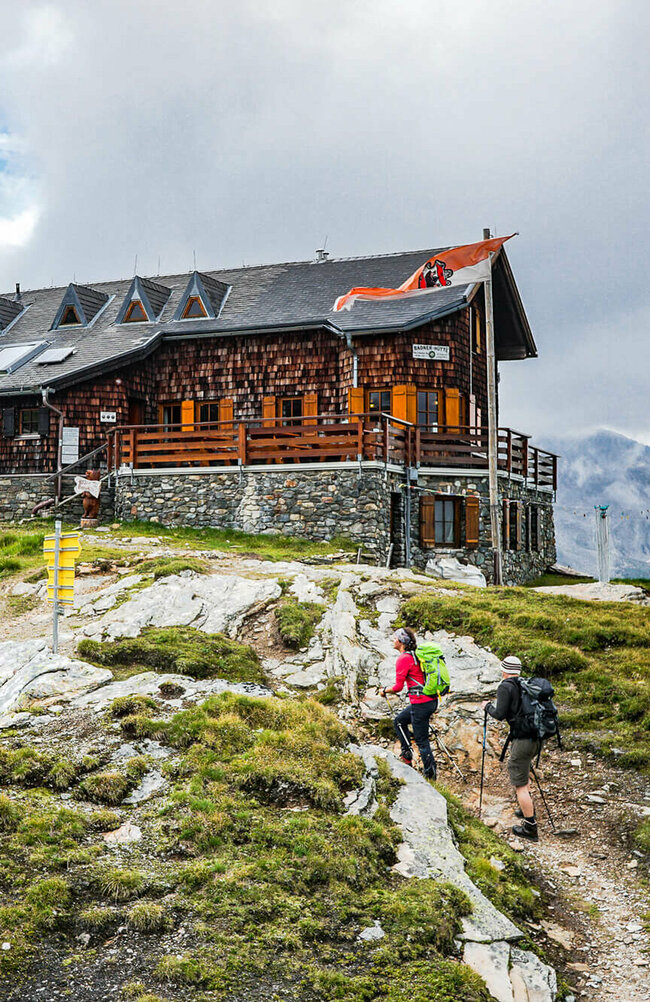 Zwei Personen mit Wanderstöcken auf den letzten Metern vor der Badener Huette am Adlerweg in Osttirol.