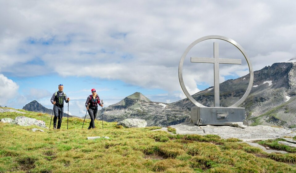 Weitwandern auf der Glocknerkrone in Osttirol, Etappe 2: Wanderer am Gipfelkreuz Spinewitrol mit Blick nach Norden auf den Medelzkopf nahe Kals am Großglockner.